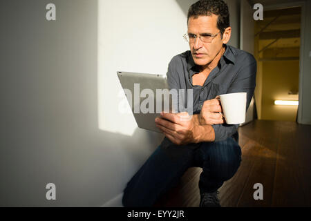 Hispanic businessman using digital tablet in office hallway Stock Photo