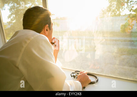 Hispanic doctor looking out window Stock Photo