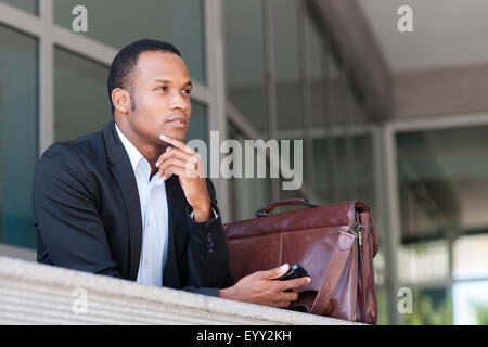 Black businessman thinking outside building Stock Photo