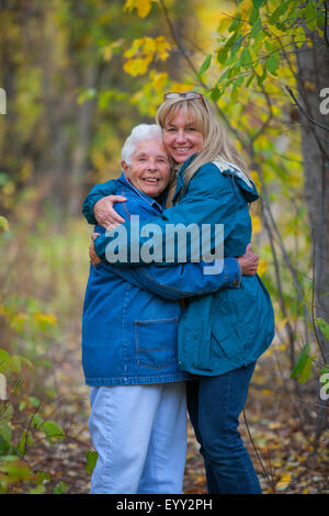 Caucasian mother and daughter hugging in forest Stock Photo