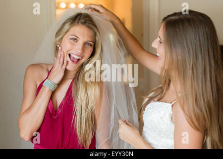 Caucasian bridesmaid wearing veil of bride Stock Photo