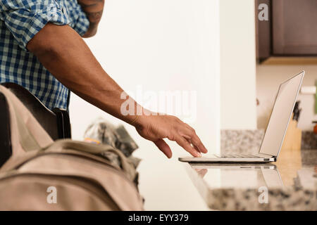 Mixed race man using laptop on counter Stock Photo