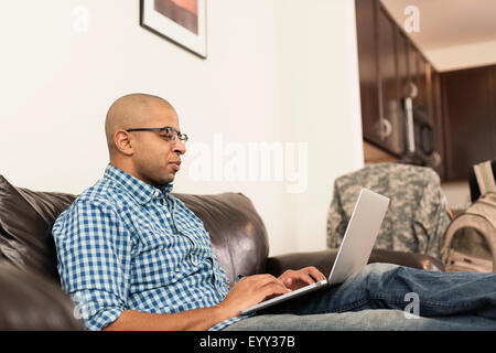 Mixed race man using laptop on sofa in living room Stock Photo