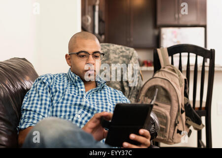 Mixed race man using digital tablet on sofa in living room Stock Photo