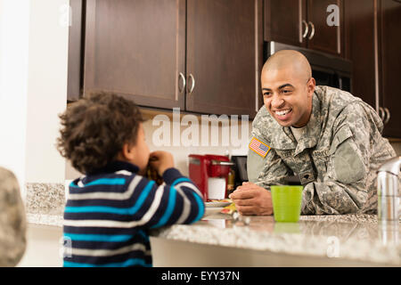 Mixed race soldier father and son eating in kitchen Stock Photo