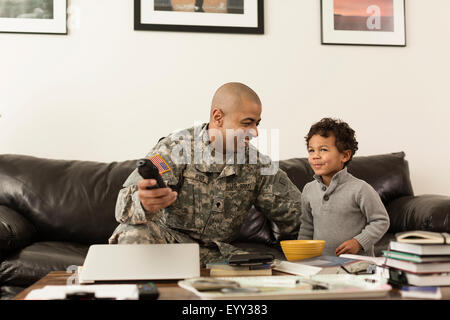 Mixed race soldier father and son watching television in living room Stock Photo