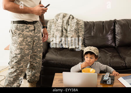 Mixed race father soldier and son relaxing in living room Stock Photo