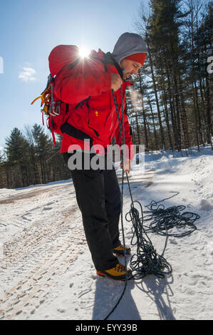 Hiker untangling ropes in snowy forest Stock Photo