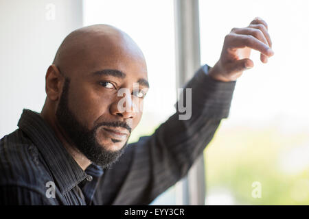 Black man standing at window Stock Photo
