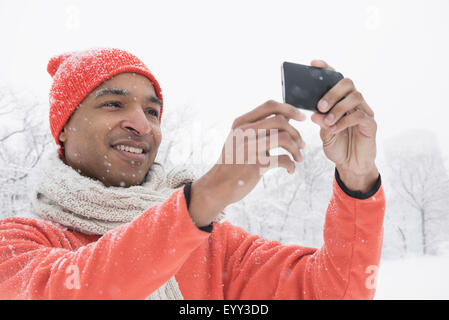 Black man using cell phone in snow Stock Photo