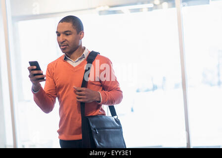 Black businessman with cell phone and messenger bag Stock Photo