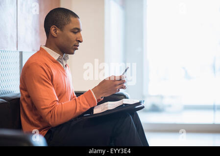 Black businessman using cell phone in office lobby Stock Photo