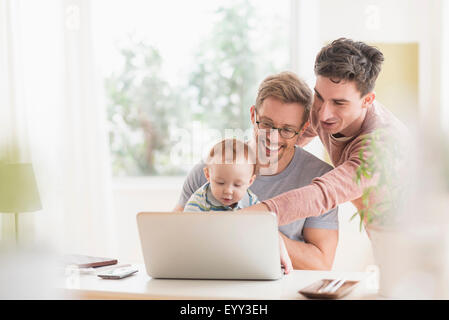 Caucasian gay fathers and baby using laptop Stock Photo