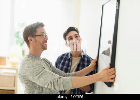 Caucasian gay couple hanging picture on wall Stock Photo