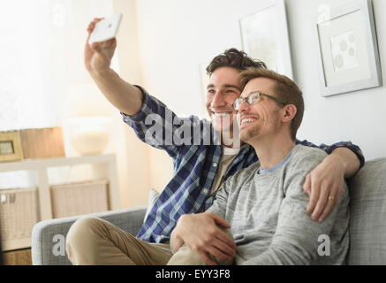 Caucasian gay couple taking selfie on sofa Stock Photo