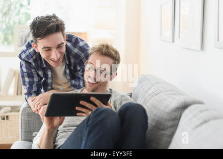 Caucasian gay couple using digital tablet on sofa Stock Photo