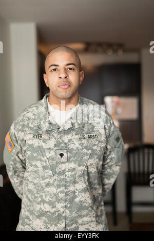 Mixed race soldier standing in living room Stock Photo