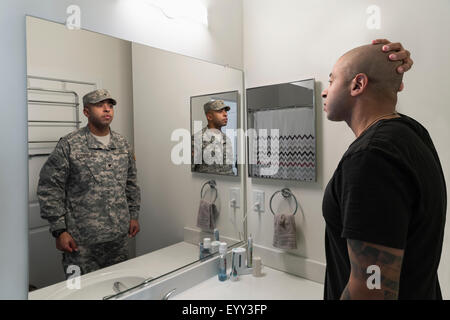 Mixed race man seeing soldier in mirror Stock Photo