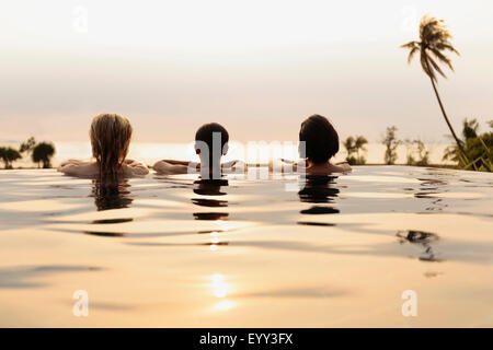 Women admiring scenic view in infinity pool Stock Photo