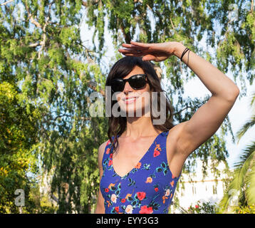 Hispanic woman shielding her eyes from sun Stock Photo