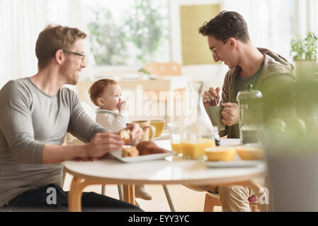 Caucasian gay fathers and baby eating breakfast Stock Photo