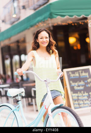 Chinese woman pushing bicycle on sidewalk