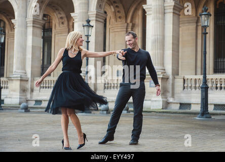 Caucasian couple dancing in courtyard Stock Photo