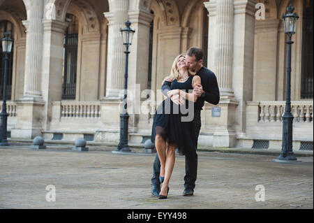 Caucasian couple dancing in courtyard Stock Photo