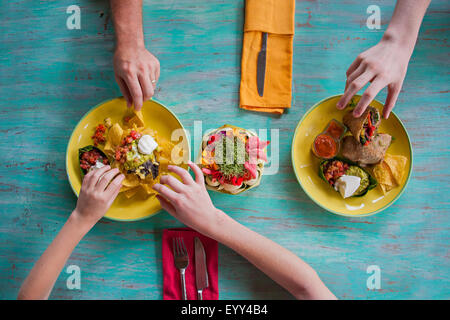 High angle view of hands reaching for food on plates Stock Photo