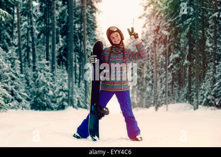 Caucasian snowboarder making peace sign in snowy forest Stock Photo