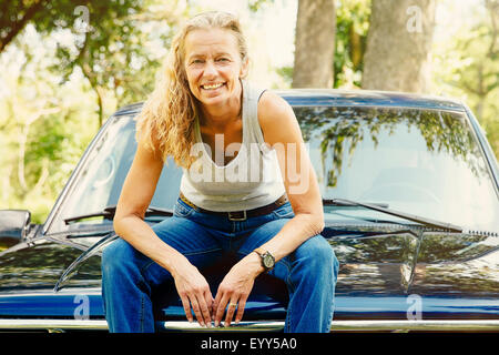 Caucasian woman sitting on car hood Stock Photo