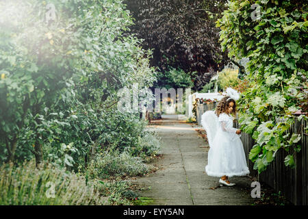 Mixed race girl wearing angel costume on sidewalk Stock Photo