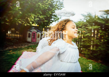 Mixed race girl wearing angel costume in backyard Stock Photo