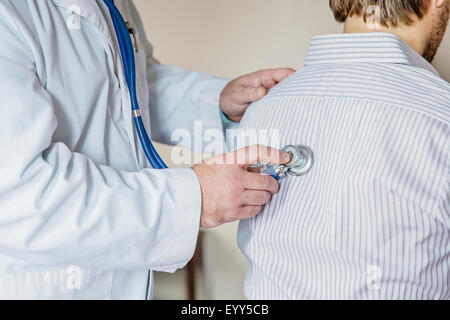 Caucasian doctor listening to heartbeat of patient Stock Photo