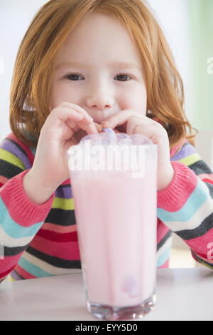 Caucasian girl blowing bubbles in strawberry milk Stock Photo