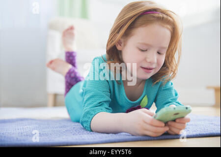Caucasian girl using cell phone on floor Stock Photo