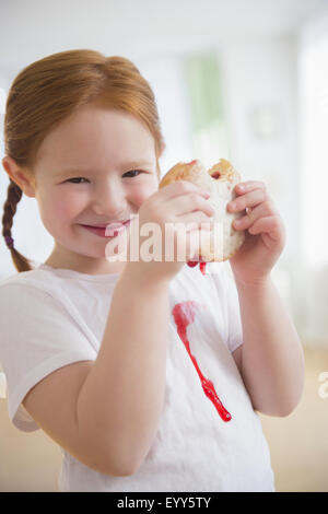 Caucasian girl eating messy jelly donut Stock Photo