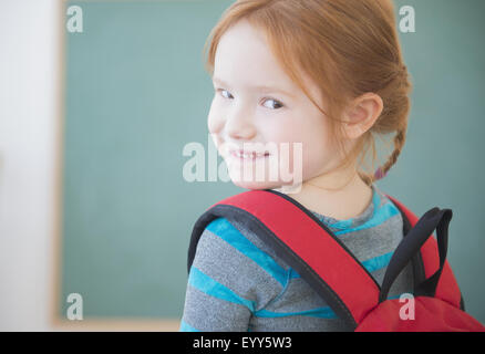 Caucasian girl wearing backpack in classroom Stock Photo