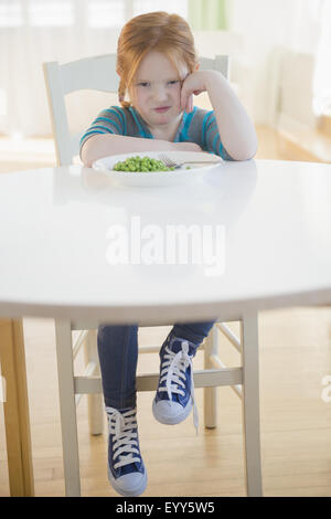 Caucasian girl pouting at plate of vegetables Stock Photo