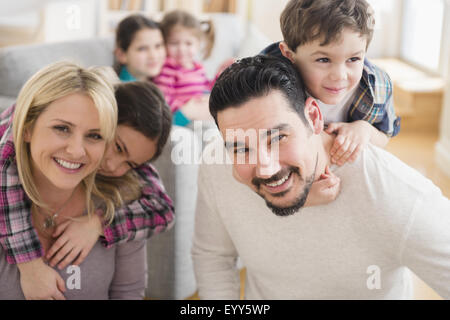 Caucasian parents carrying children piggyback in living room Stock Photo