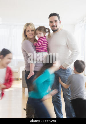 Caucasian parents busy with running children Stock Photo