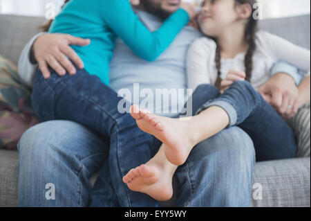 Caucasian father and daughters hugging on sofa Stock Photo