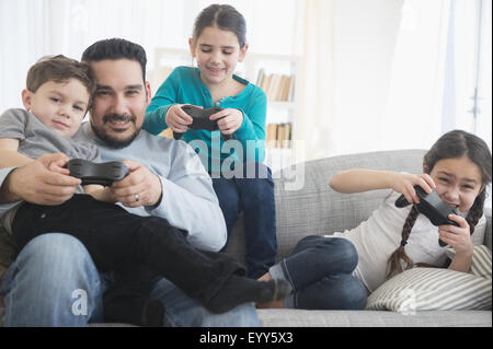 Caucasian father and children playing video games on sofa Stock Photo