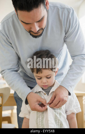 Caucasian father buttoning shirt for son Stock Photo