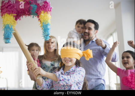 Caucasian girl hitting pinata at birthday party Stock Photo