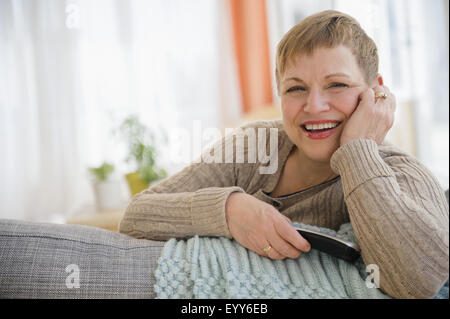 Caucasian woman holding remote control on sofa Stock Photo