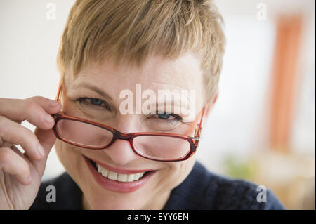 Caucasian woman peering over eyeglasses Stock Photo