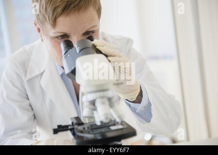 Caucasian scientist looking through microscope in lab Stock Photo
