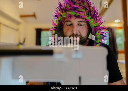 Caucasian man wearing fuzzy hat using sewing machine Stock Photo