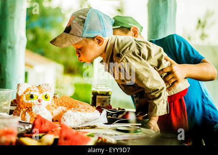 Caucasian boy blowing out candles on birthday cake Stock Photo